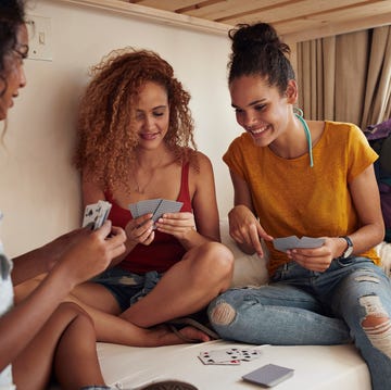 young women playing cards in bunk bed, at youth hostel