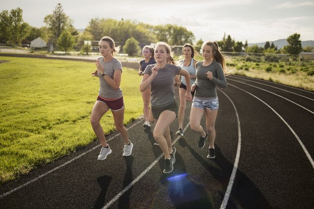 Young women runners rounding turn on track