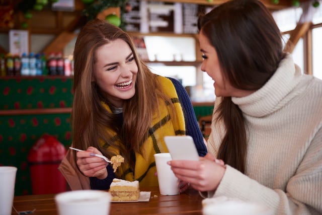Young women smiling over text message on mobile phone