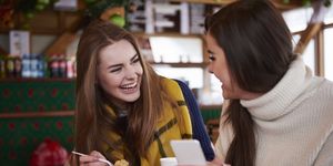 Young women smiling over text message on mobile phone