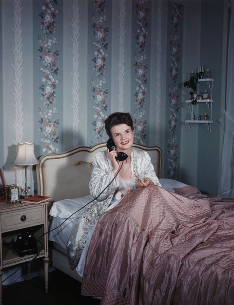 young women talking on telephone in bed