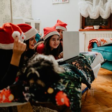 young women wearing santa hats using laptop during christmas holidays