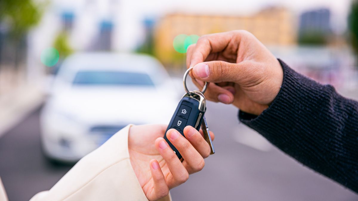 two hands exchanging keys after trading in a car at a dealership