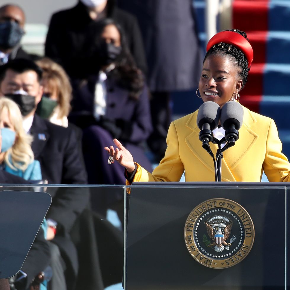 amanda gorman wearing a yellow coat and speaking behind a podium
