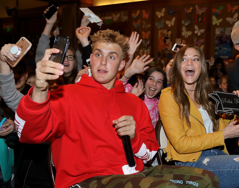 jake paul looking into a cell phone and holding a microphone