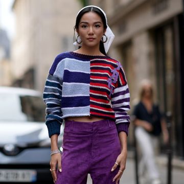 yoyo cao draagt gestreepte trui, paarse broek en witte sjaal tijdens paris fashion week