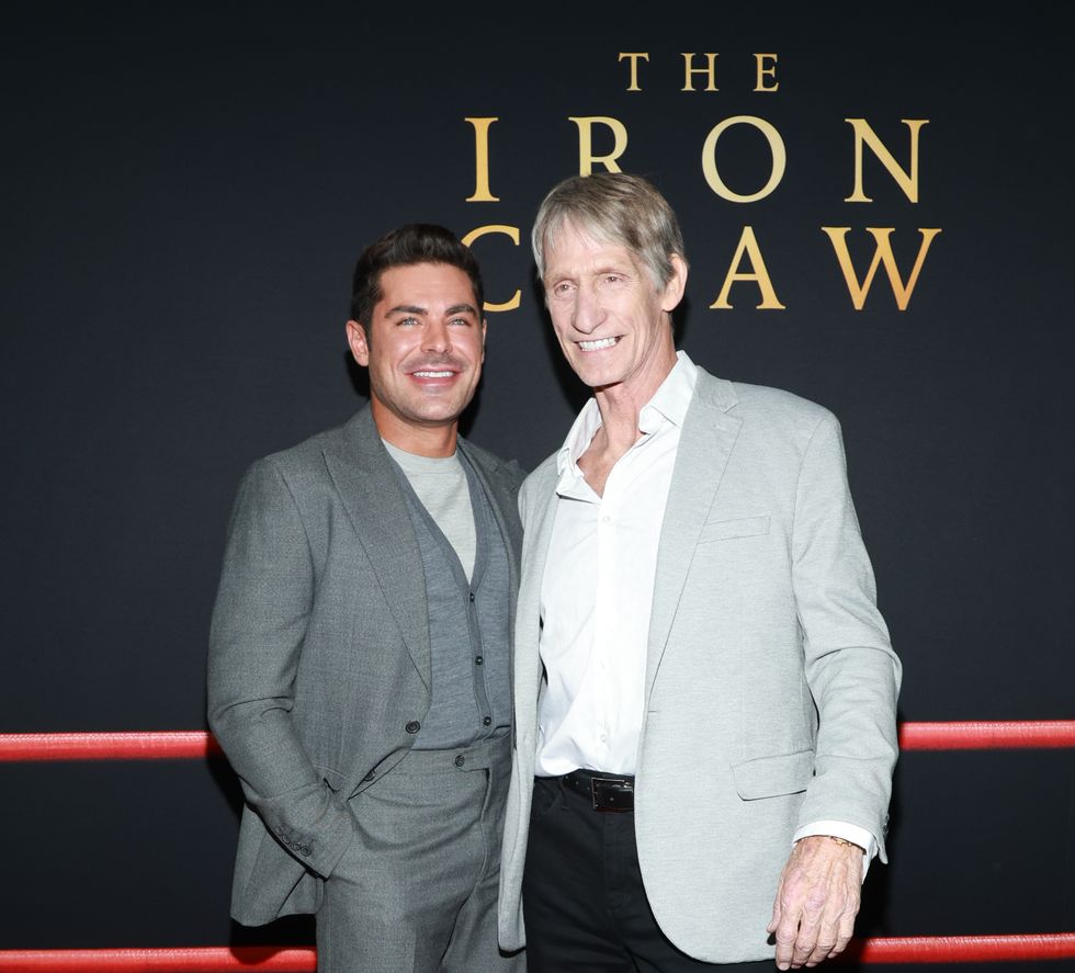 zac efron smiling and embracing kevin von erich for a photo