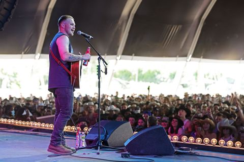 zach bryan performing on stage as an audience looks on