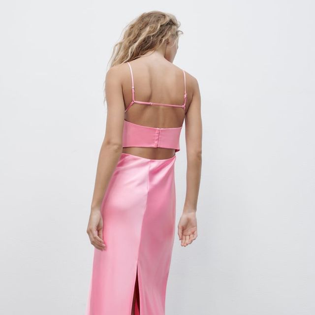 a model wears a zara pink satin slip dress that has gone viral on tiktok with back cut outs and a fluted hem