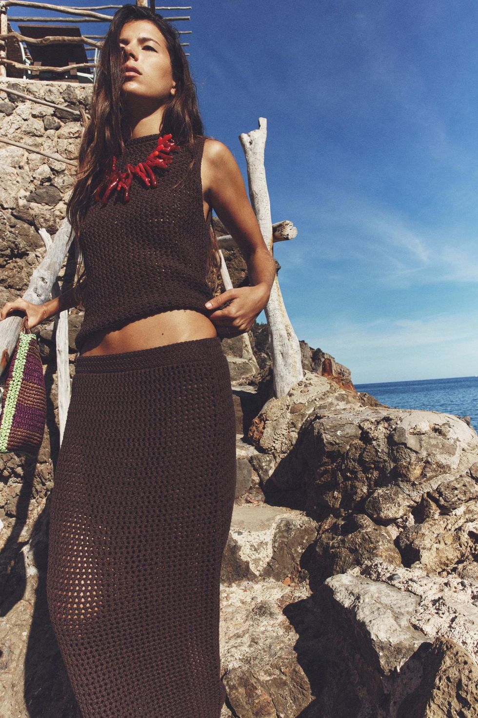 a woman in a garment holding a sword on a rocky beach