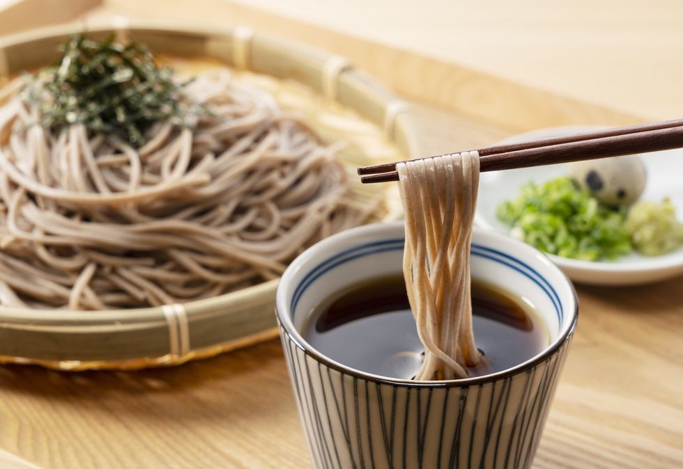 zaru soba and condiments on a wooden table soba noodles are dipped in noodle soup