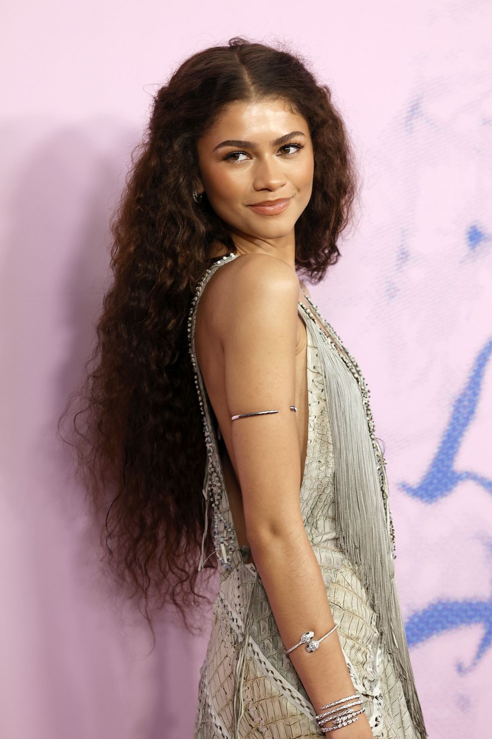 zendaya with long fluffy hair and a beige woven fringed gown