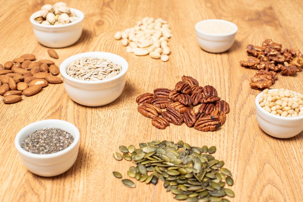 a variety of nuts and seeds arranged on a wooden table