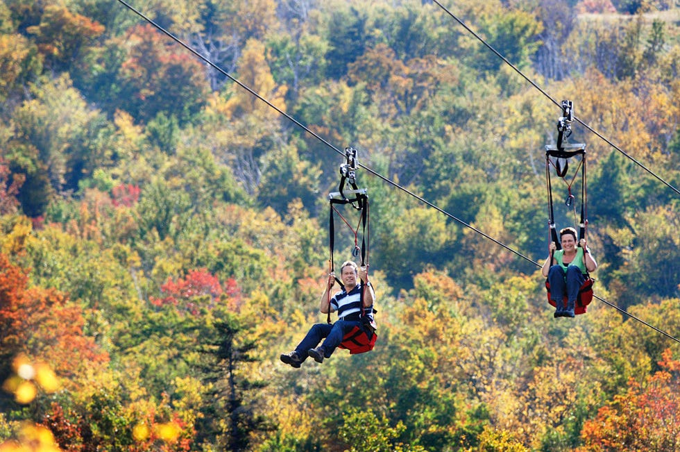 Twee bezoekers glijden aan de tokkelbaan ZipRider in Wildcat Mountain in het White Mountain National Forest van New Hampshire