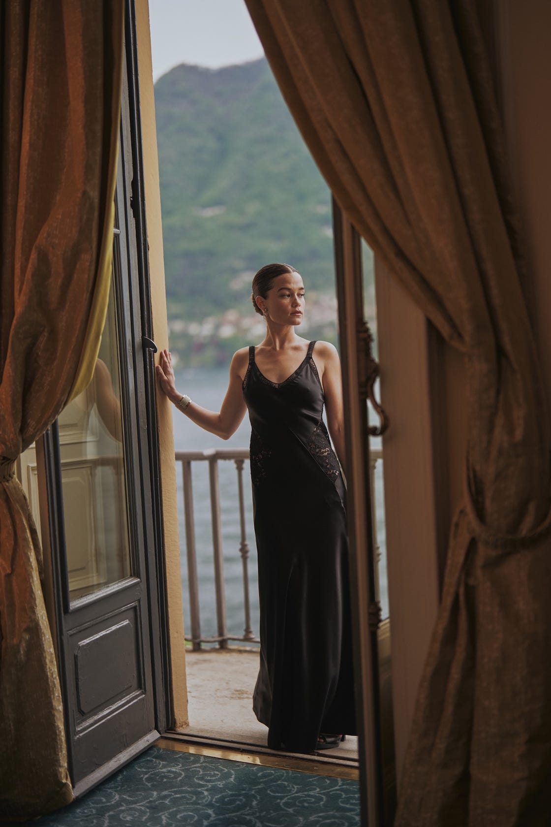 a person in formal attire standing on a balcony with a scenic view