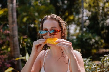 een vrouw eet mango op het strand