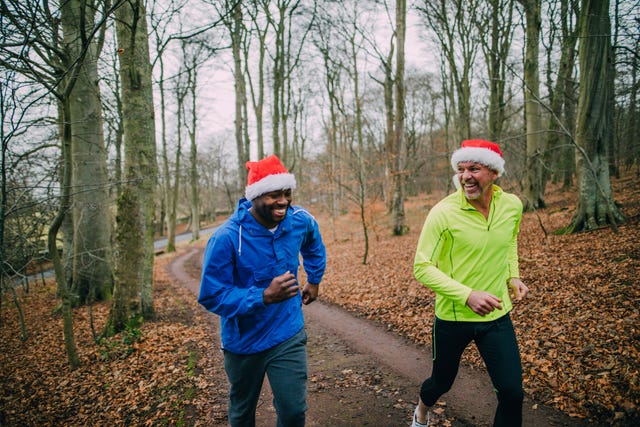 twee mannen lopen hard in het bos met een kerstmuts op