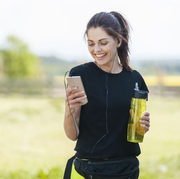 een vrouw houdt haar drinkfles en telefoon vast na het hardlopen