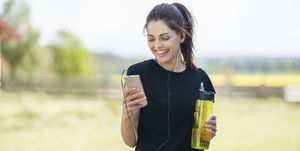een vrouw houdt haar drinkfles en telefoon vast na het hardlopen