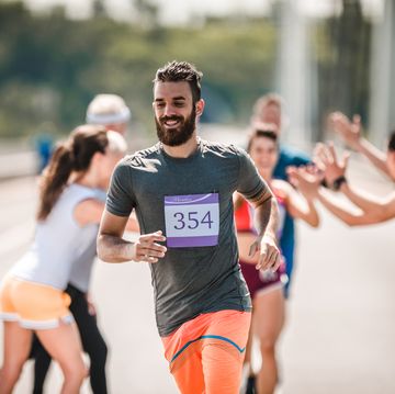 een man loopt hard met een lach op zijn gezicht tijdens een marathon