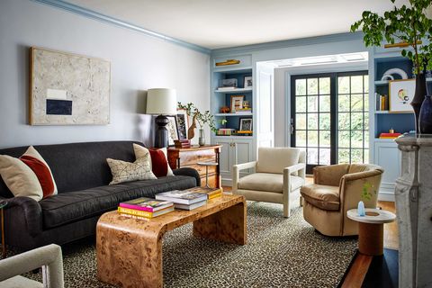 sitting room with black sofa, wooden coffee table with coffee table books, light blue painted walls