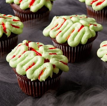 chocolate cupcakes decorated with green frosting and red gel food coloring to look like zombie brains