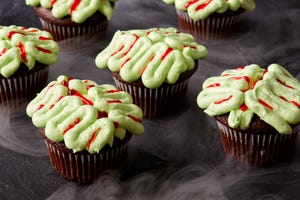 chocolate cupcakes decorated with green frosting and red gel food coloring to look like zombie brains