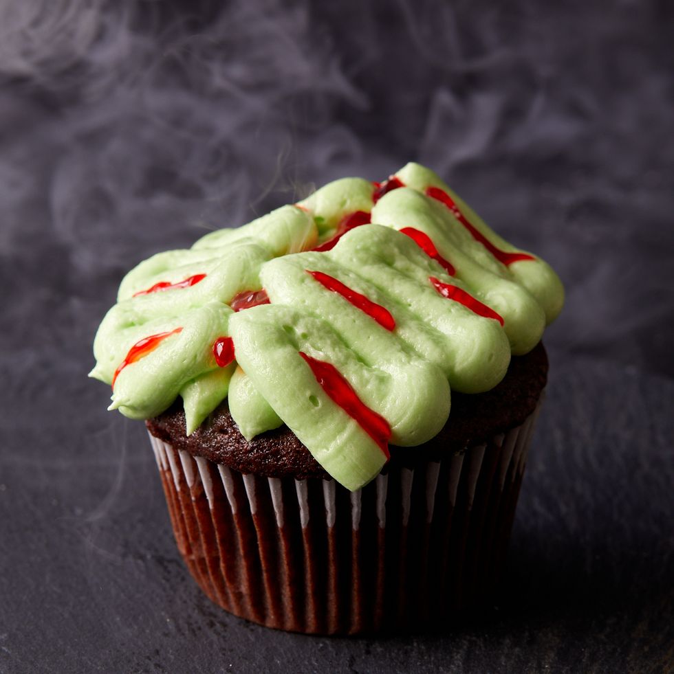 chocolate cupcakes decorated with green frosting and red gel food coloring to look like zombie brains