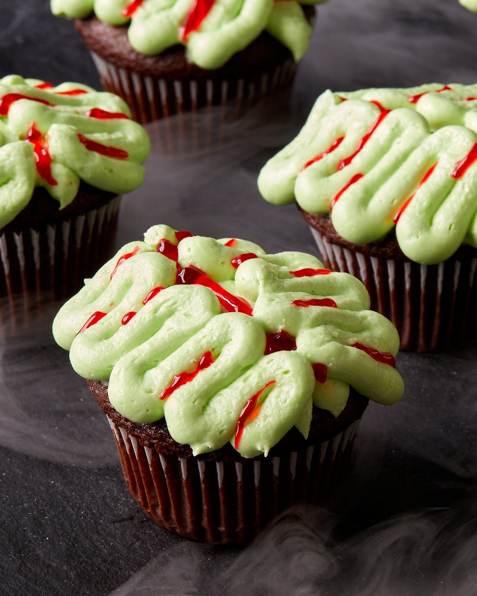chocolate cupcakes decorated with green frosting and red gel food coloring to look like zombie brains