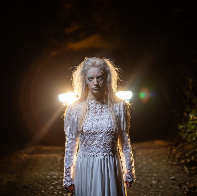 zombie in wedding dress standing on a road at night