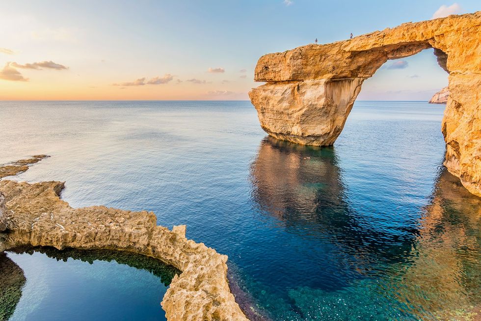 Bezoekers wandelen over het Blauwe Raam een gat in de kliffen van Dwerja Bay op Gozo het tweede eiland van Malta