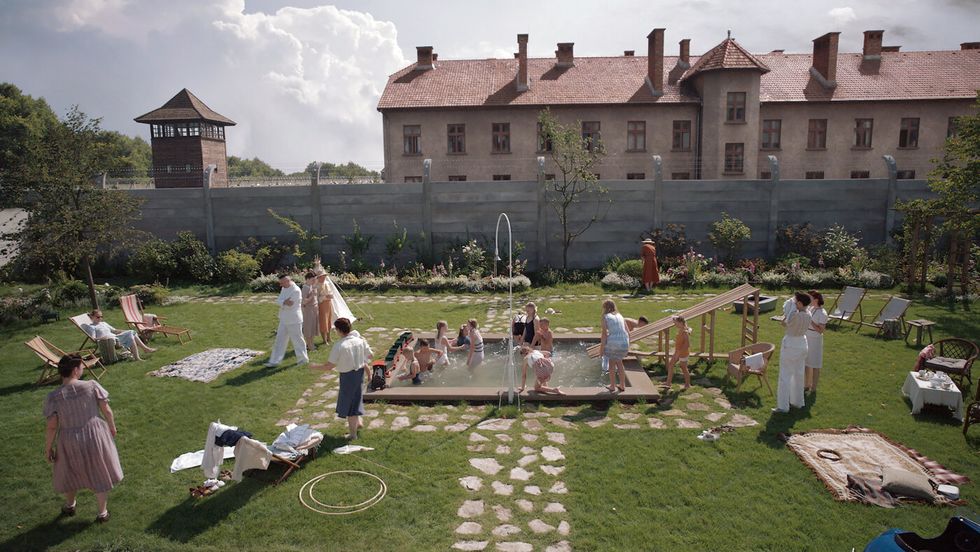 a group of people playing in a yard with chairs and tables