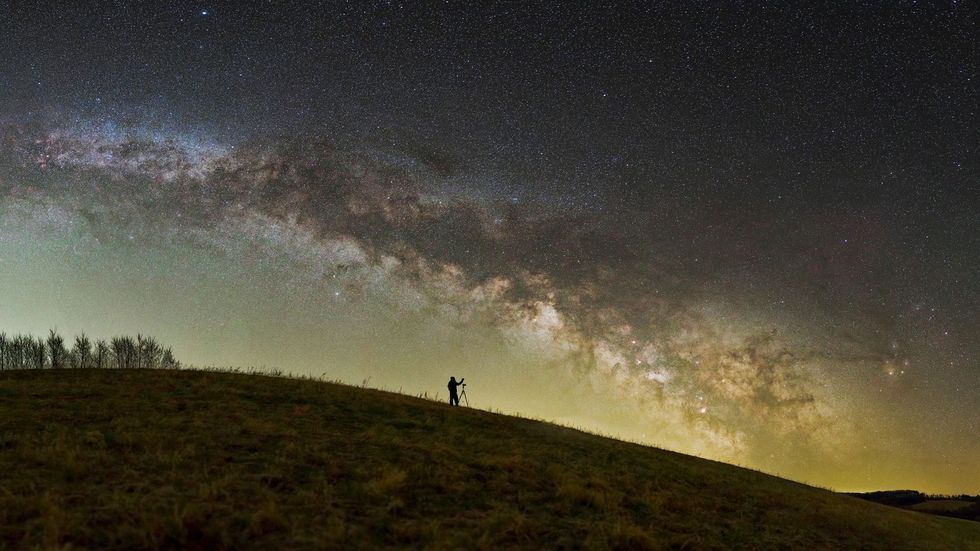 Een fotograaf zet zijn apparatuur op onder de sterrenhemel van het Nationaal Landschapsbeschermingsgebied Zselic in Hongarije