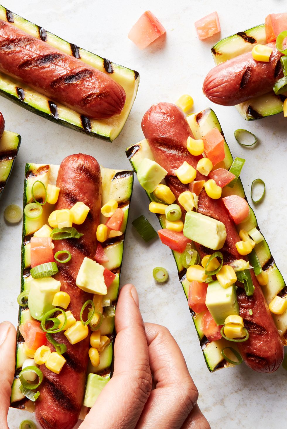 grilled hot dogs in between grilled zucchini topped with avocado salsa