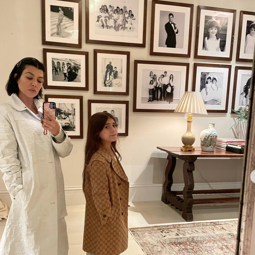 a woman taking a selfie with another woman in a room with pictures on the wall