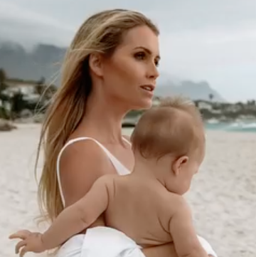 a woman holding a baby on a beach