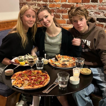 a group of people sitting at a table with pizzas