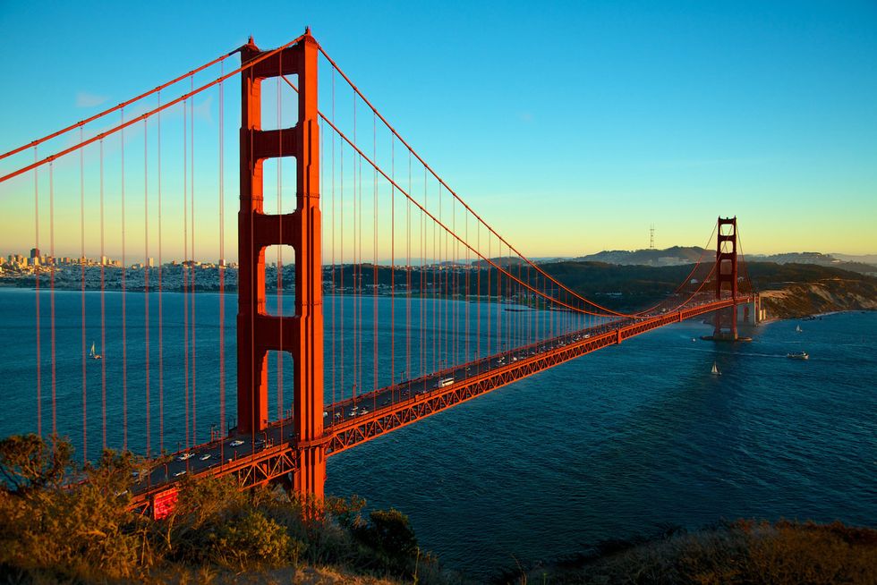 a large red bridge over water with golden gate bridge in the background