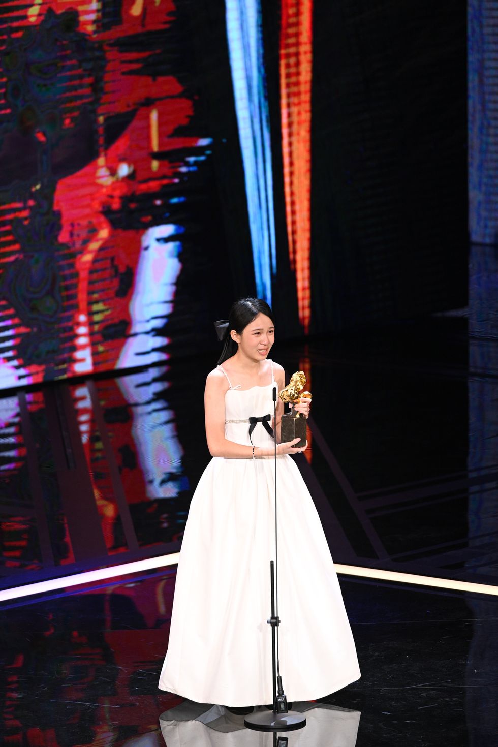 a person in a white dress holding a trophy
