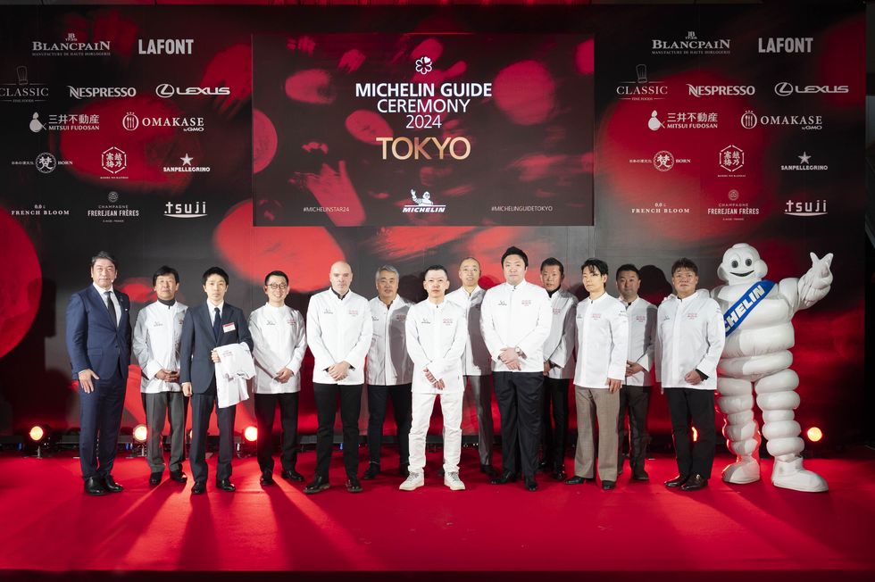 a group of people who got michelin stars posing for a photo with a person in a garment