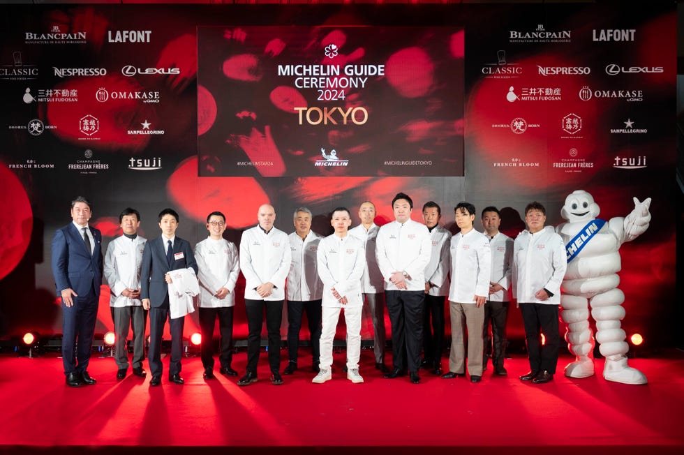 a group of people who got michelin stars posing for a photo with a person in a garment