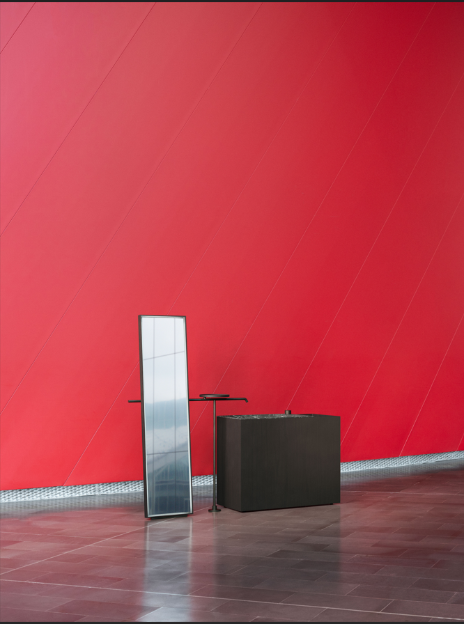 a red wall with a black box and a black box on a wooden floor