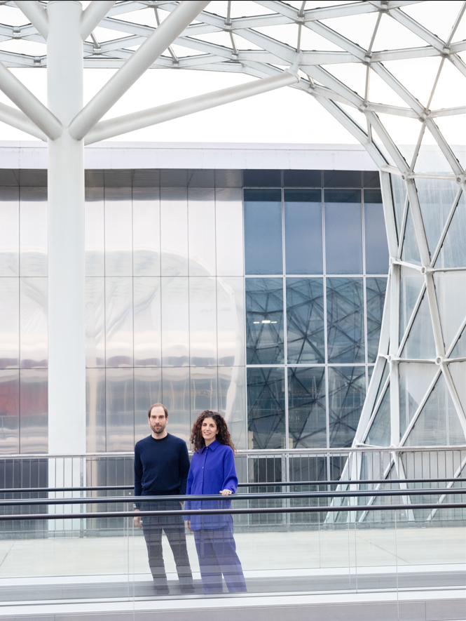 a man and woman standing in front of a large glass building