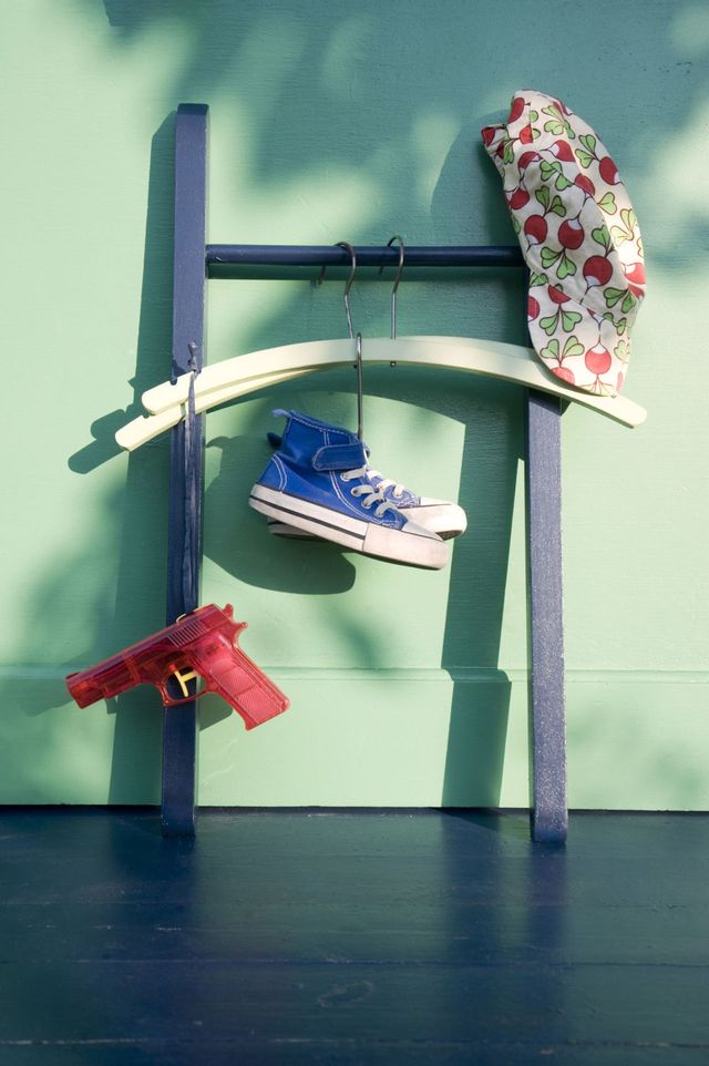 Old wooden chair converted to a rack with trainers, a sun hat and a red toy gun