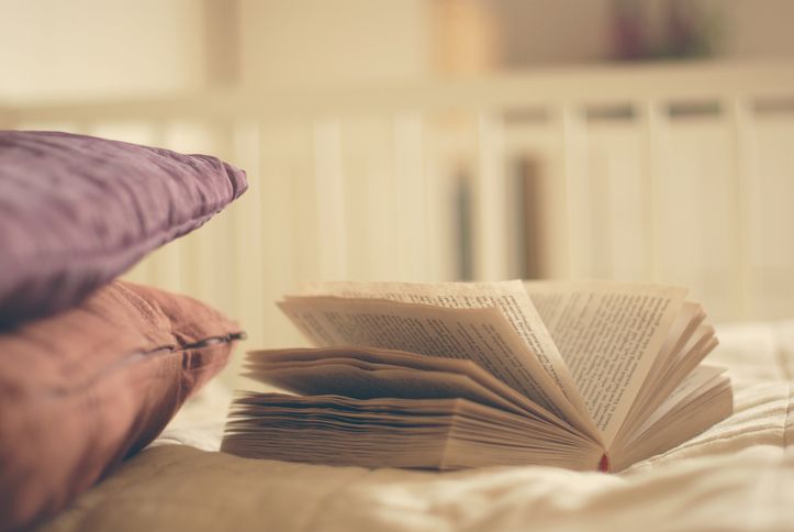 An open book and two pillows on a bed