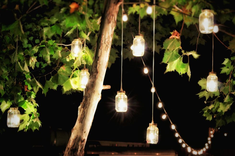 Illuminated Decorations Hanging From A Tree In A Garden At Night