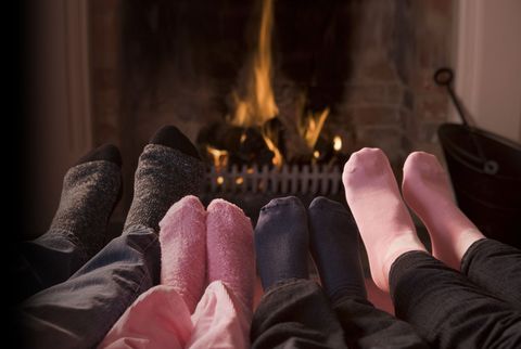 Feet (grey, navy blue and pink socks) in front of a wood burning stove