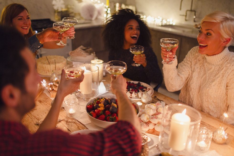 Enthusiastic friends toasting champagne glasses at candlelight Christmas dinner