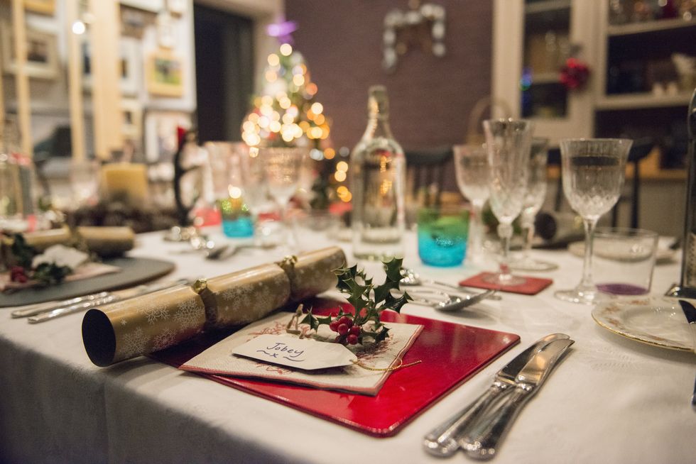 A table laid for a Christmas meal, with silver and crystal glasses and a Christmas tree in the background.