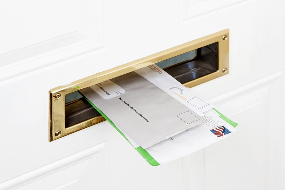 Several pieces of mail stuck in a front door mail slot, close-up